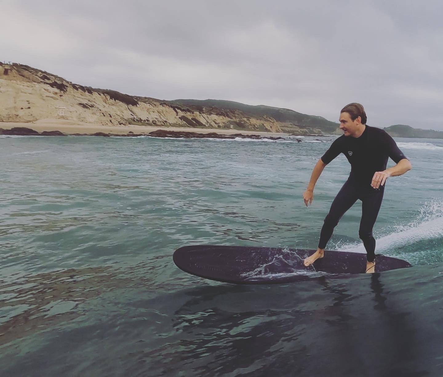 Surfer riding a VESL Soft Top Longboard on a small wave