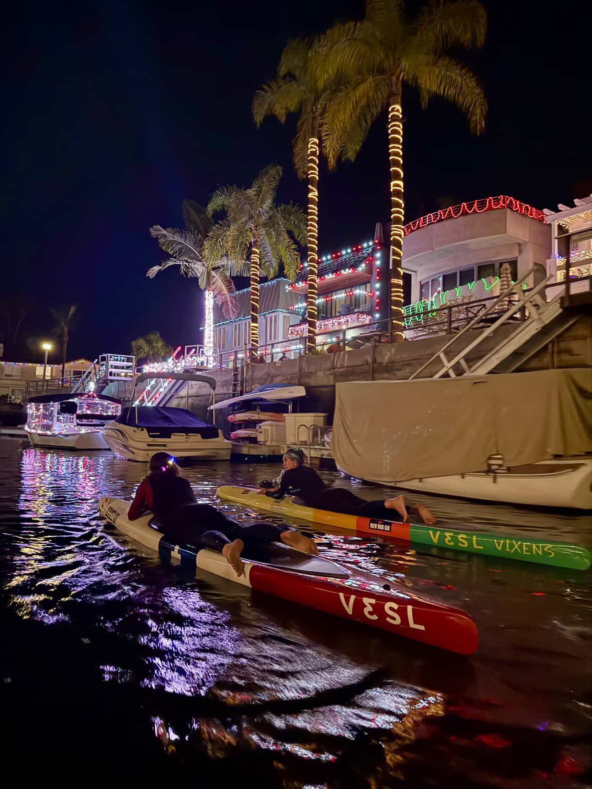 Prone paddlers enjoying a holiday night paddle in Naples, Long Beach under Christmas lights
